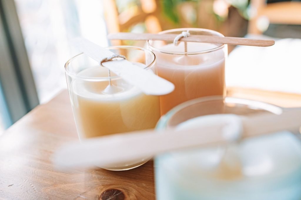 A serene close-up of three handmade scented candles in glass holders on a wooden surface.